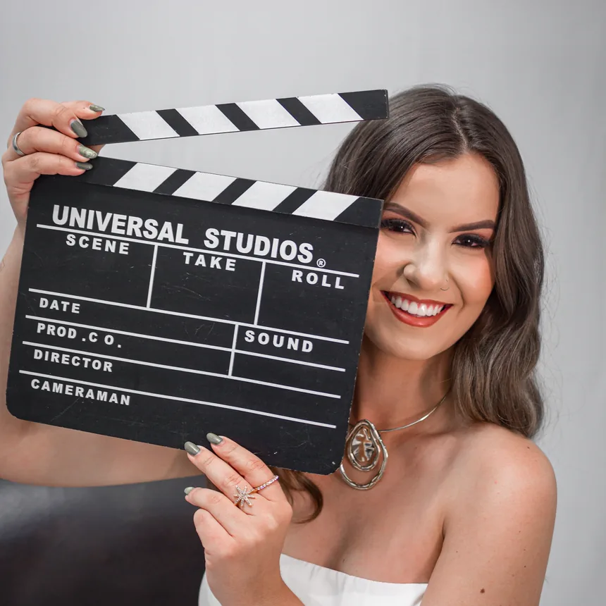 Izabelle Rezende sorrindo, com uma claquete de cinema nas mãos